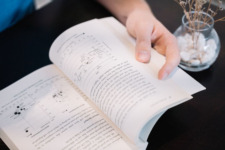 Close-up of a hand turning pages in a book with data charts and text.